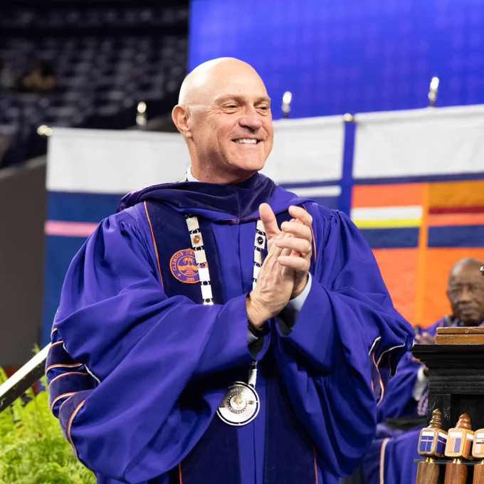President Jim Clements smiles while clapping on stage during graduation at Clemson. 