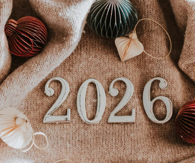 The numbers 2026 on top of a beige background with trinkets around it.
