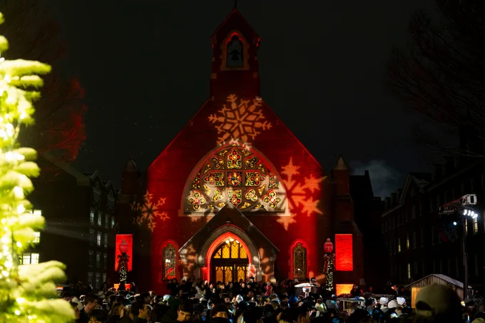 Dahlgren Chapel lights up in a red hue with projected snowflakes during the annual Georgetown Christmas Tree Lighting.