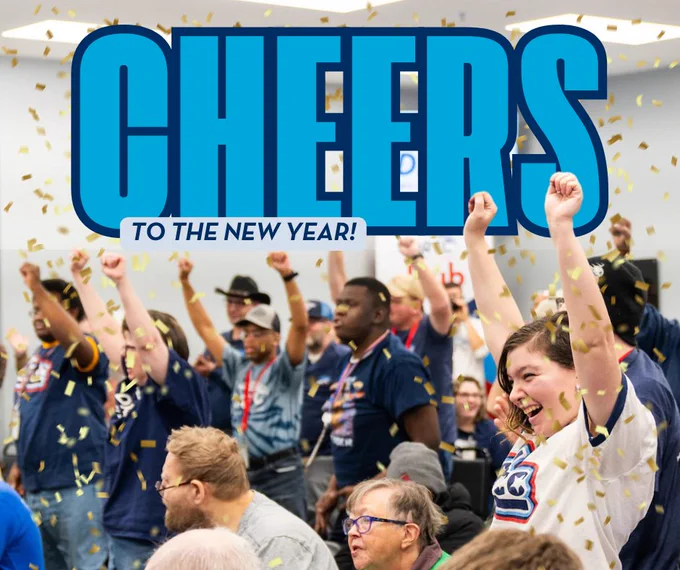 CHEERS TO THE NEW YEAR! Image of large group of people cheering with their arms raised with confetti covering them. 
