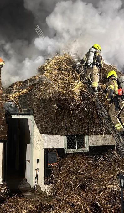 Firefighters on the roof of the thatched cottage