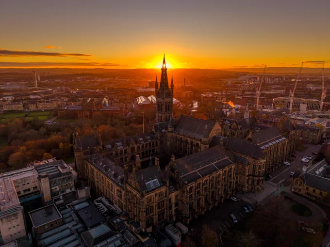 University of Glasgow building from the sky with sun setting behind the tower.