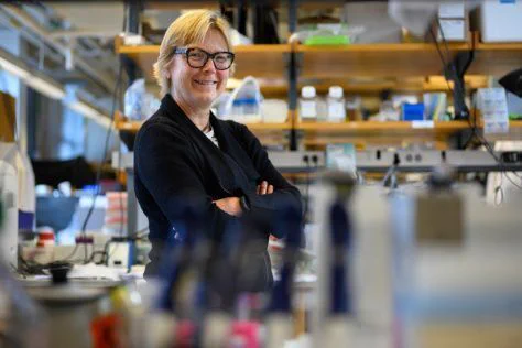 Photo of Linda Griffith, wearing a black blazer, in her laboratory.