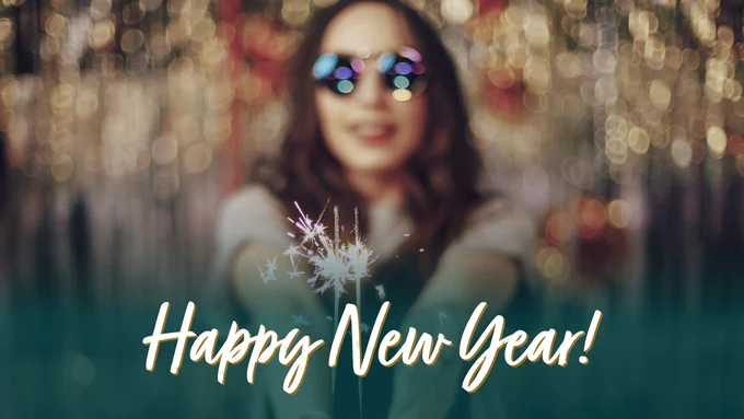 Person holding a sparkler with 'Happy New Year!' text, against a blurred background of shimmering lights.