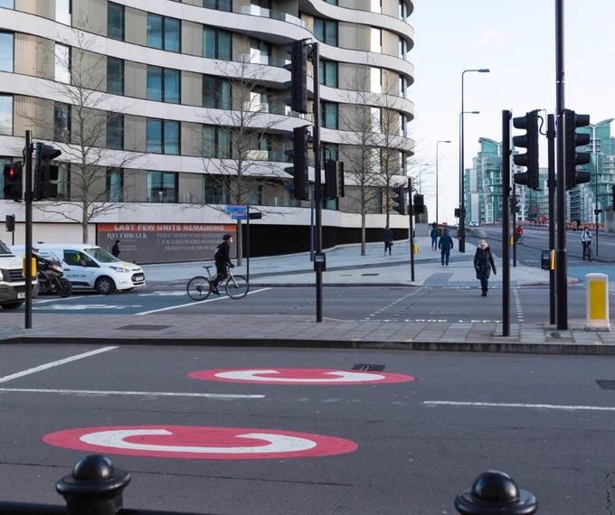 On the ground are two large red painted circles, each with a large letter "C" painted in the middle, indicating a central London Congestion. Charge zone.