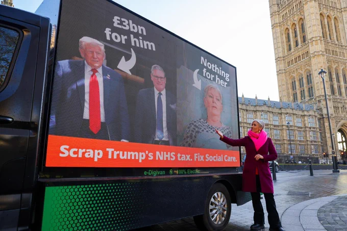 IMAGE: Lib Dem Deputy Leader Daisy Cooper MP pointing at the ad van that says: ''Scrap Trump's NHS tax. Fix social care. 