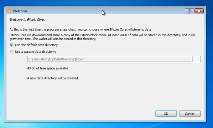 Screenshot of the Bitcoin Core “Welcome” setup screen on a Windows 7–style desktop. The window title reads “Welcome” and displays the message “Welcome to Bitcoin Core.” The interface explains that this is the first time the program is launched and asks the user to choose where Bitcoin Core will store its data. The text states that Bitcoin Core will download and store a copy of the Bitcoin blockchain, that at least 20 GB of data will be stored in the selected directory, and that the data size will grow over time. Two radio-button options are shown: “Use the default data directory” and “Use a custom data directory.” The custom directory field displays a Windows file path pointing to the user’s AppData roaming Bitcoin folder, with a browse button on the right. Below, the interface indicates that 43 GB of free space is available and that a new data directory will be created. At the bottom right are “OK” and “Cancel” buttons. The clean, instructional layout emphasizes Bitcoin Core’s role as