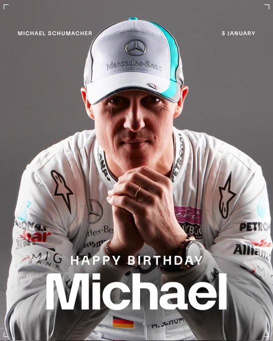 Michael Schumacher wearing his Mercedes race overalls and cap, leaning forward on his elbows. There is bold white text that says 'Happy Birthday Michael'.