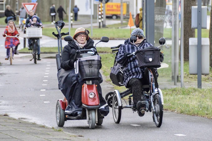 Two women on Scootmobiles on a bicycle lane in The Netherlands