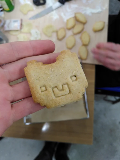 Ein Keks in Form des pixeligen Alpaka-Kopfes, gehalten von einer Hand.