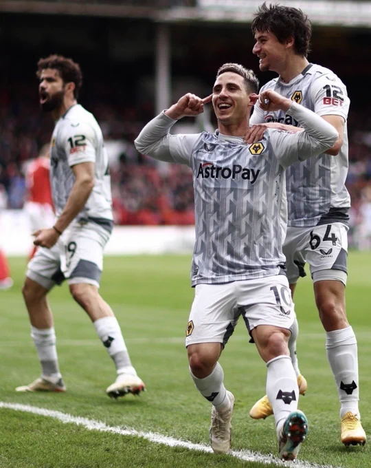 Daniel Podence celebrates scoring a goal by running to the home end at The City Ground and putting his fingers in his ears and smiling. Diego Costa and Hugo Bueno are in the background and Wolves are wearing their Third Choice Shirt which is grey/white with a geometrical shaped pattern