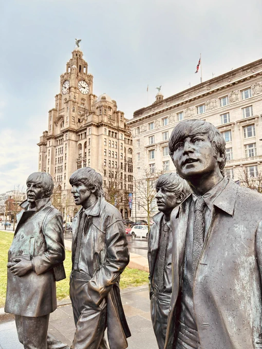 A statue of the Beatles In front of the liver building.