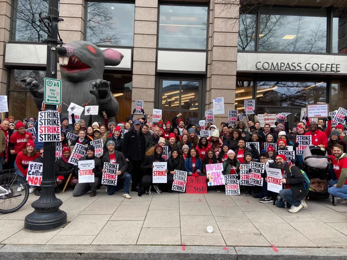A series of group photos of strikers. Dozens of people pose for a group photo in front of The Washington Post building with strike signs. An inflatable rat looms above them.
