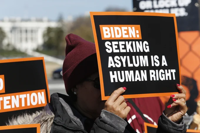 A protester holds a sign that reads: "Biden: Seeking Asylum is a Human Right."