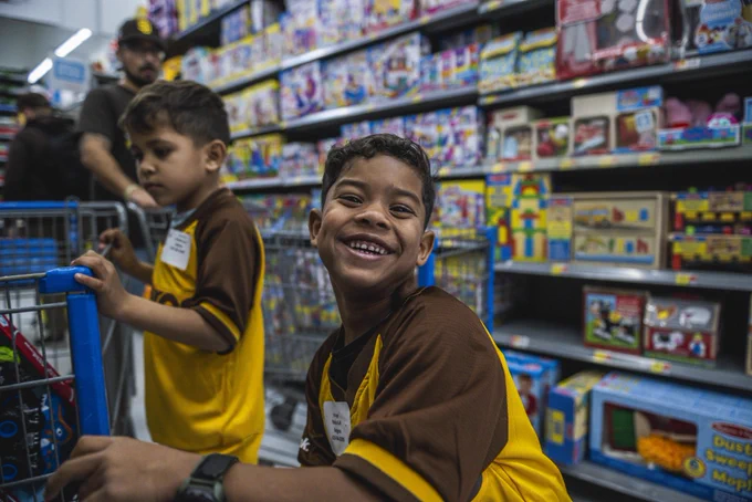 Photo of a student from Perkins Elementary School during today’s holiday shopping event at Walmart. He is wearing a yellow and brown Padres jersey and is smiling big for the camera as he holds onto a shopping cart.