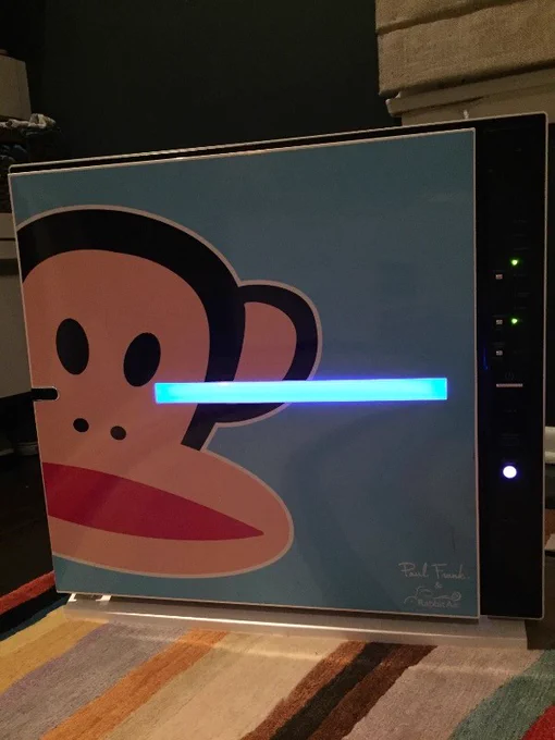 A Paul Frank designed Rabbit Air MinusA2 air purifier, featuring the iconic monkey face on a vibrant blue background, illuminating a room with both style and purified air