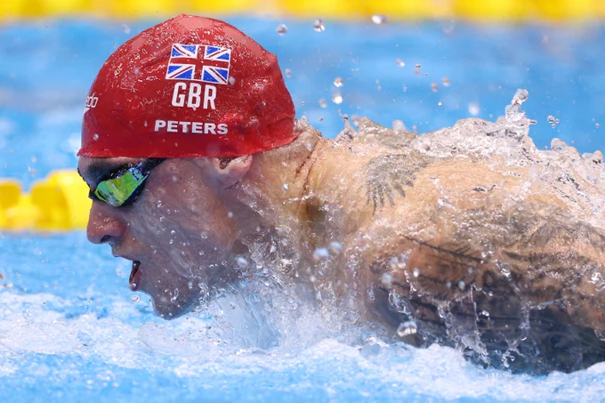 A side-on angle of Jacob Peters mid-butterfly stroke, wearing a GB cap