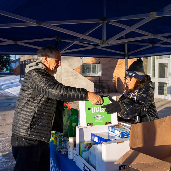 Community member handing off food donations at food drive.