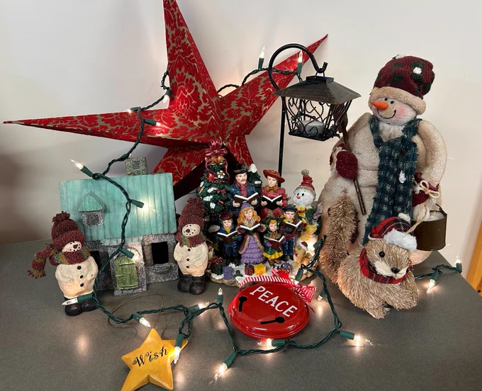 Various Christmas decor items set atop a table with a strand of lights wrapped around