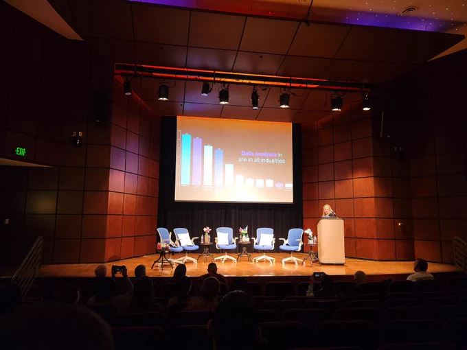 Robin Hunt at the podium. Behind her is a slide that says "data anaylsts are all industries". 