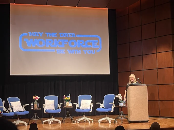 Robin Hunt at the podium with a slide that says "May the Data Workforce be with you" 