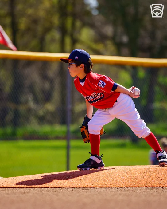 Little League pitcher leans forward on the mound