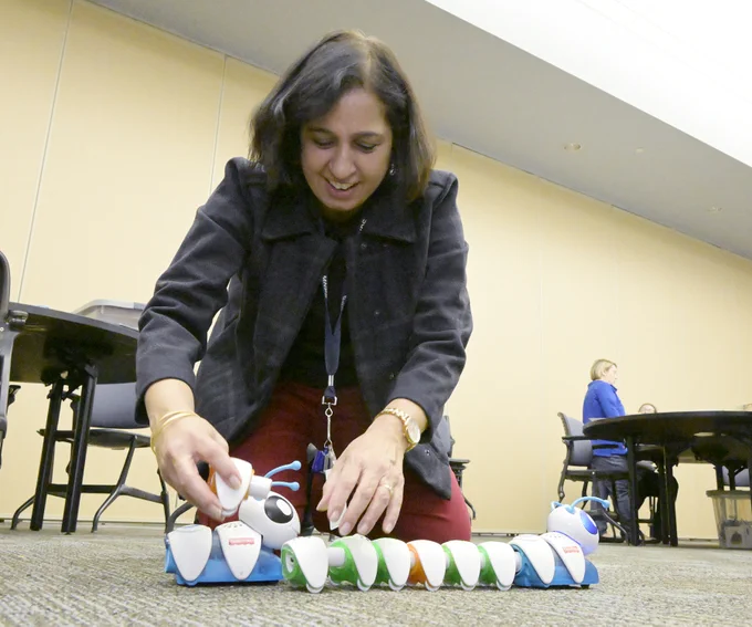 Teacher putting together a computerized toy caterpillar. 