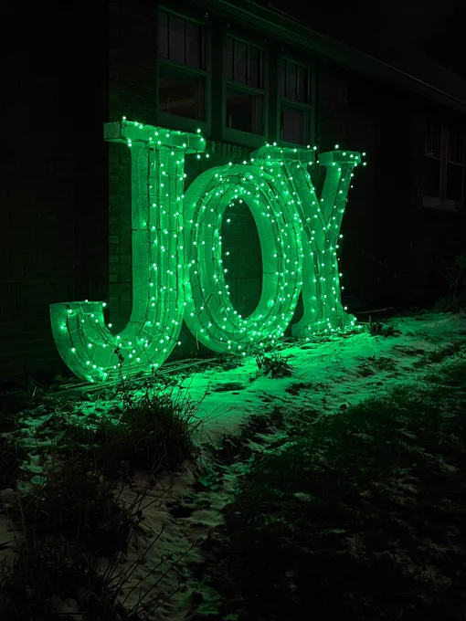 This is an outdoor 6 foot JOY holiday decoration with green lights.
