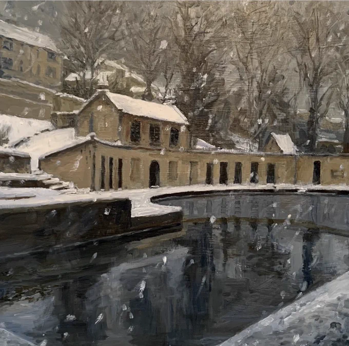 A winter view of a crescent shaped Georgian building behind an outdoor swimming pool. There is snow falling and settled on the ground. There are trees and house in the background.