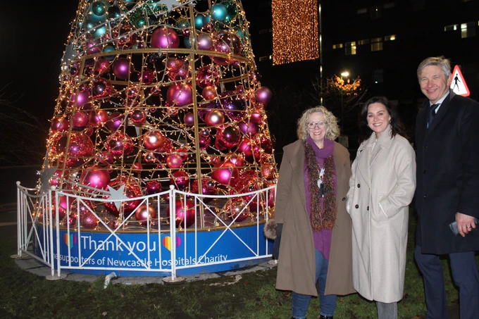 The lit up tree at the Freeman, with Jill Baker, Chair of the Newcastle Hospitals Charity Committee, Jill Halfpenny, the voice of Geordie Hospital, and Professor Sir John Burn, Chairman of The Newcastle upon Tyne NHS Foundation Trust, standing beside it with smiles on their faces after the successful switch on of the festive lights there.