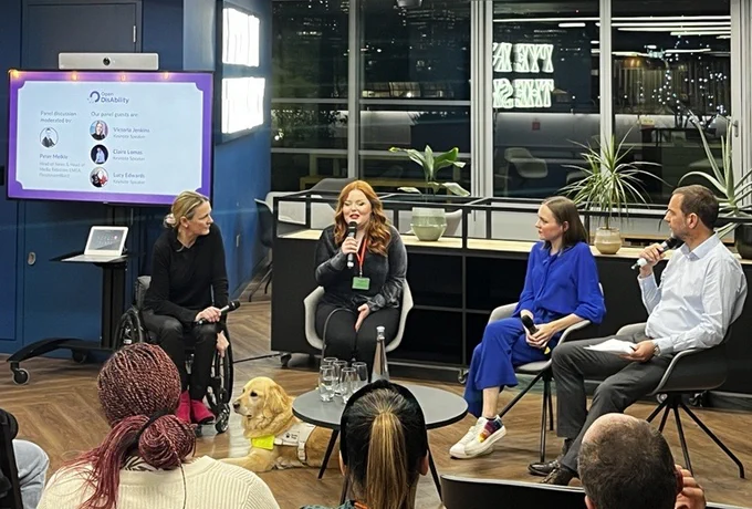 The three event speakers, Claire Lomas on the left, Lucy Edwards in the middle and Victoria Jenkins on the right, sit in discussion with the event moderator Pete Meikle sat on the far right, who has short brown hair and wearing a blue shirt.