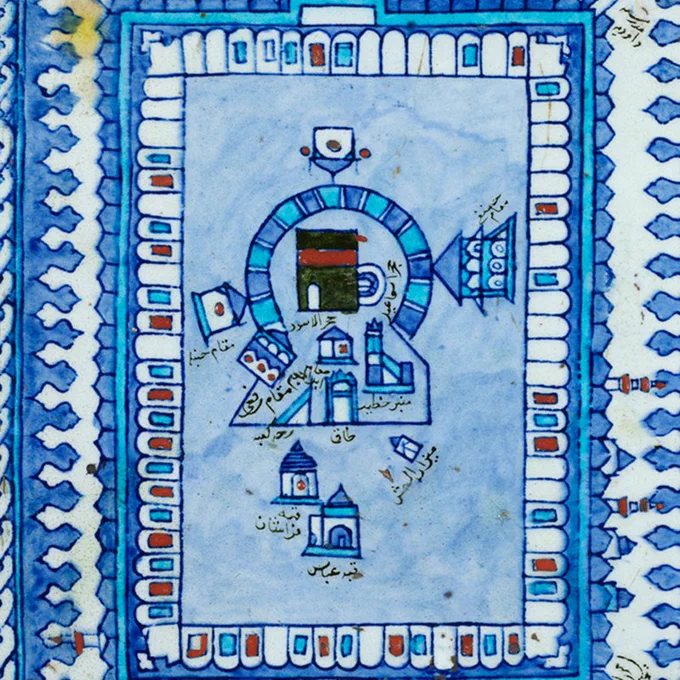 A blue, white, red, and black tile showing the Great Mosque of Mecca surrounded by a rectangular portico. The Ka‘ba is depicted as a black rectangle in the middle. 