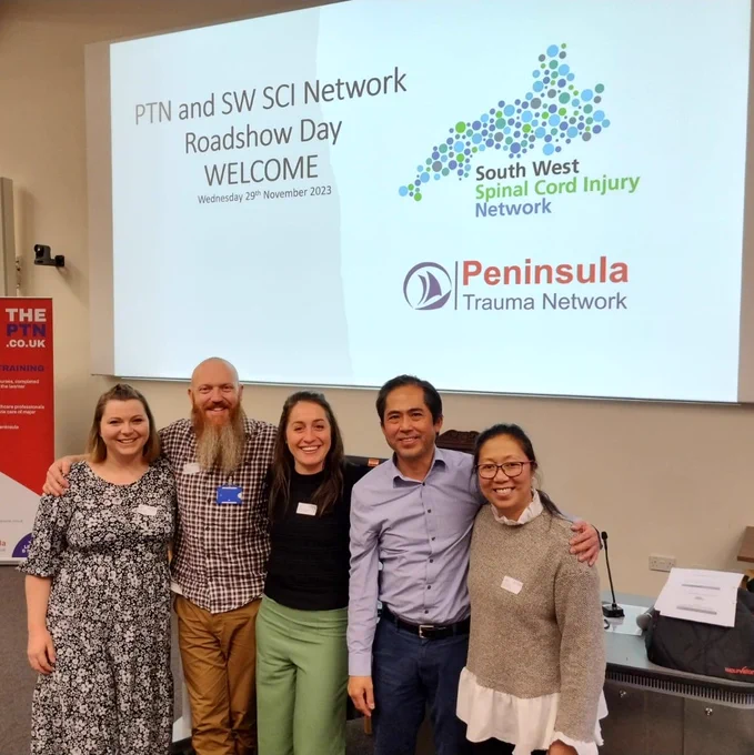 Sophie and four colleagues standing in front of a projected PowerPoint presentation 