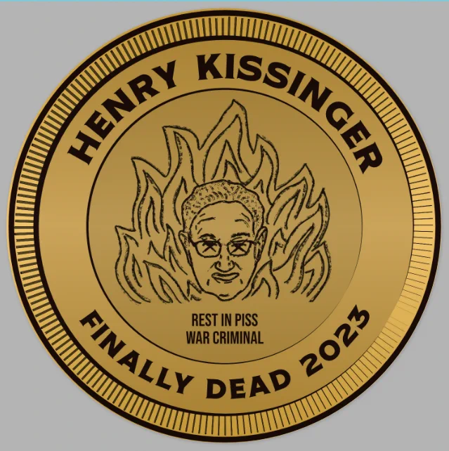 gold sticker made to look like a coin. The image is henry Kissinger in the flames of hell and it says "Henry Kissinger finally dead 2021. rest in piss war criminal.
