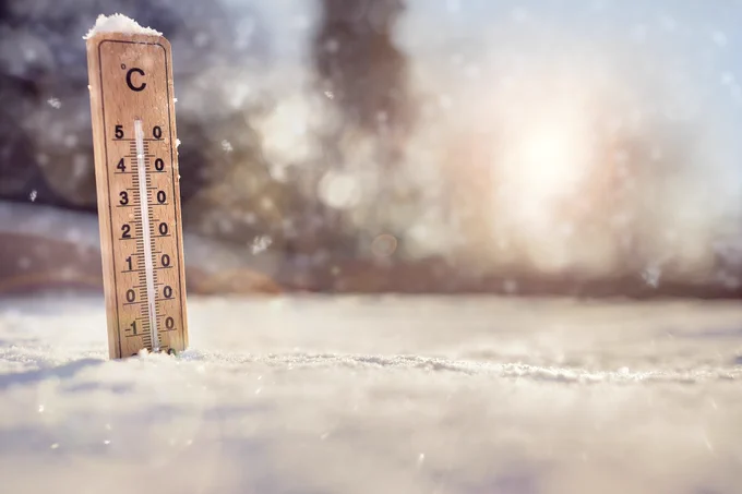 Image of a wooden thermometer, upright in snow showing a very low temperature