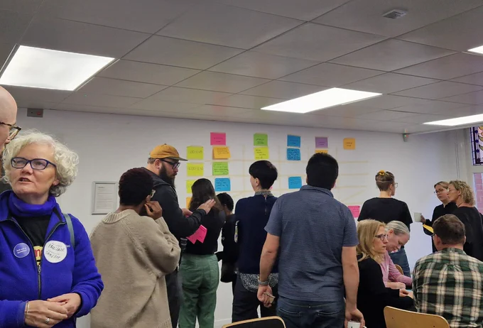 Lots of folks gathered around the unconference grid on the wall
