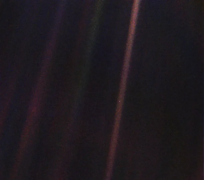 Planet Earth is a single, bright blue pixel in the vastness of space. Rays of sunlight scattered within the camera optics stretch across the scene, one of which happens to have intersected dramatically with Earth. Credit: NASA/JPL-Caltech