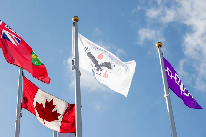 Four flags fly against the backdrop of the blue sky.