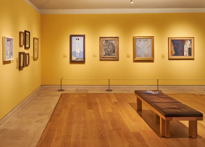 An art gallery showing various modernist images on bright yellow walls.