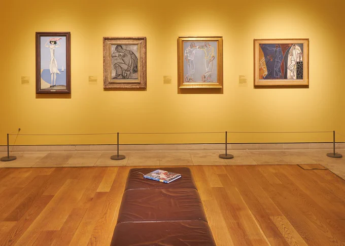 An art gallery showing various modernist images on bright yellow walls.