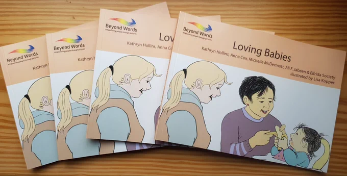 A group of Loving Babies books by Beyond Words fanned out on a wooden table. The text on the books reads: Loving Babies, Kathryn Hollins, Anna Cox, Michelle McDermott, Ali F. Jabeen & Elfrida Society, Illustrated by Lisa Kopper.