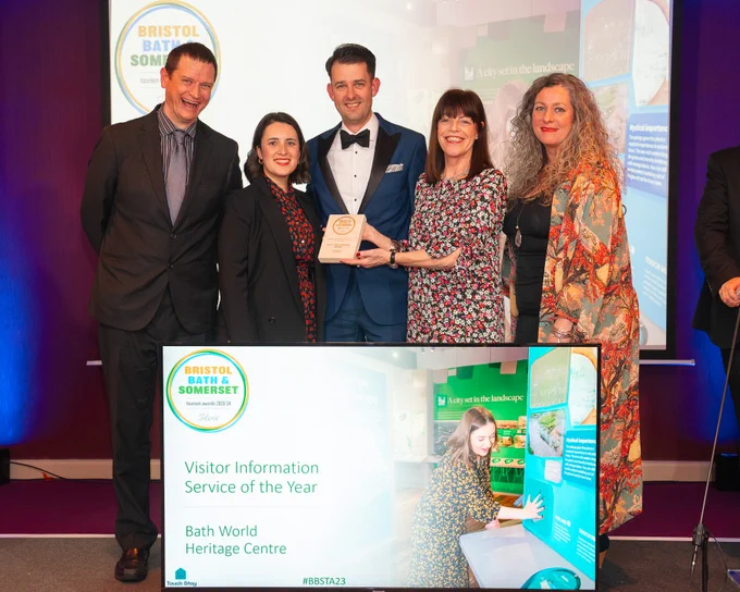 Five members of staff from the Bath World Heritage team are holding an award and smiling at the camera. 