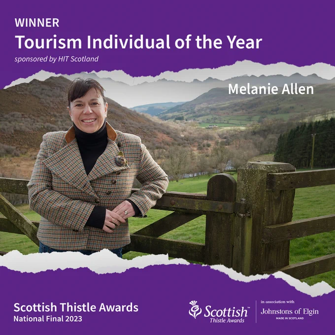 Central image shows a woman standing in front of a gate looking down onto a scene showing a valley and hills in the background. There is a purple background at the top and bottom where text reads from left to right: Winner Tourism Individual of the Year, sponsored by HIT Scotland, Melanie Allen, Scottish Thistle Awards National Final with Scottish Thistle Awards in association with Johnstons of Elgin logo