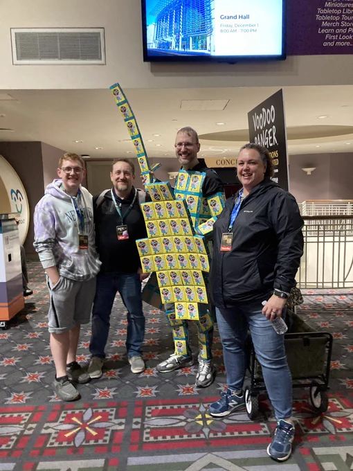 Shawn, dressed in a ridiculous suit, made out of sweet deals boxes, stands with a Kickstarter backer