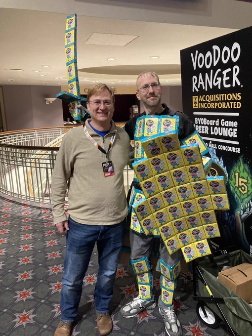 Shawn, dressed in a ridiculous suit, made out of sweet deals boxes, stands with a Kickstarter backer