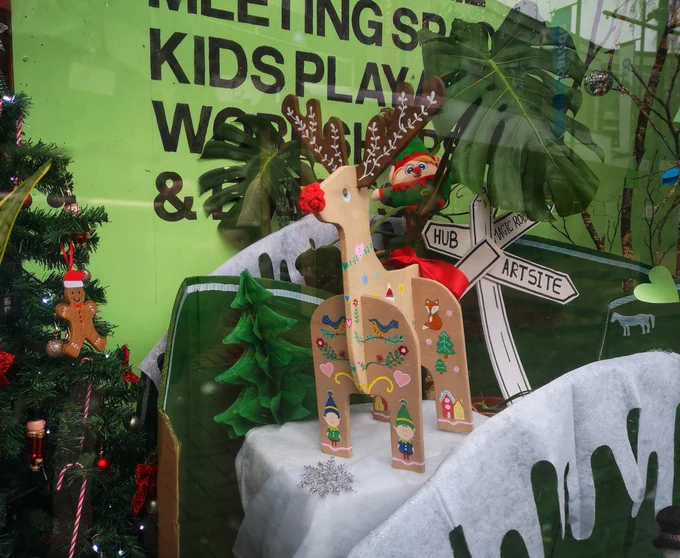 Rosie a decorated wooden reindeer sits in the window of Swindon Hub. She. Has a Christmas Tree beside her and is looking out for people visiting the Hub doing the Reindeer trail. 