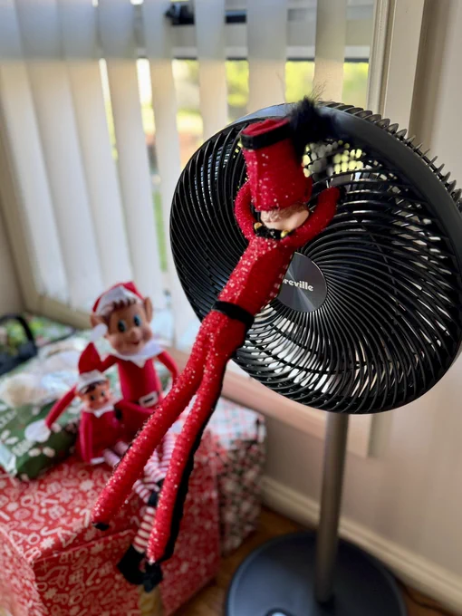 A couple of cheeky Elf’s one holding onto a fan while it’s running while two other elf’s look on.