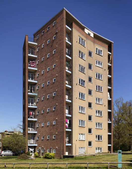 An exterior view of a ten-storey apartment block in front of a blue sky. 