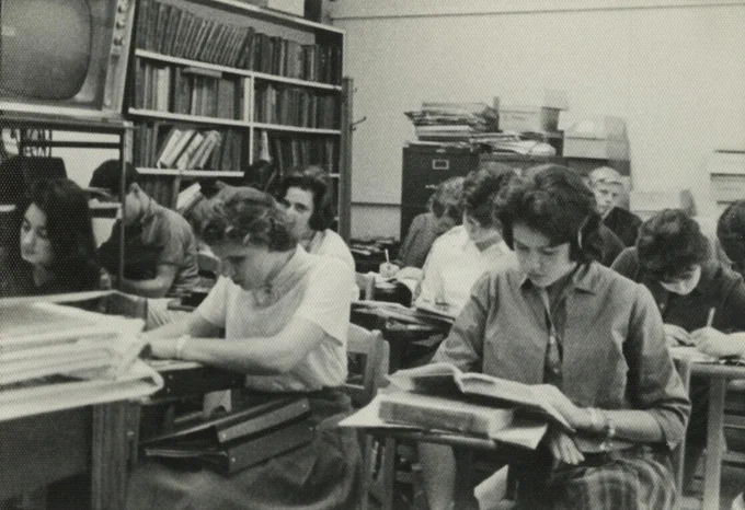 Students reading and studying at desks in a classroom. Black and White photograph