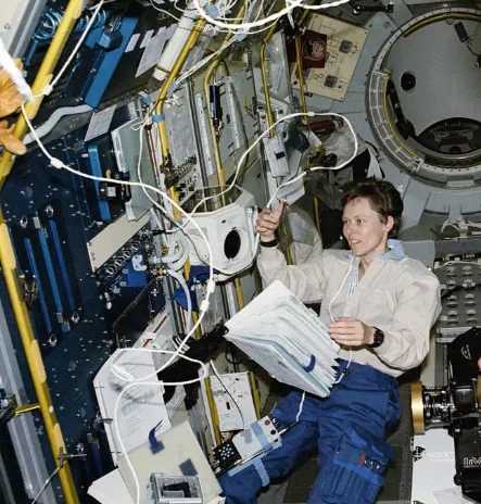 Dr. Roberta Bondar surrounded by various floating objects in microgravity.